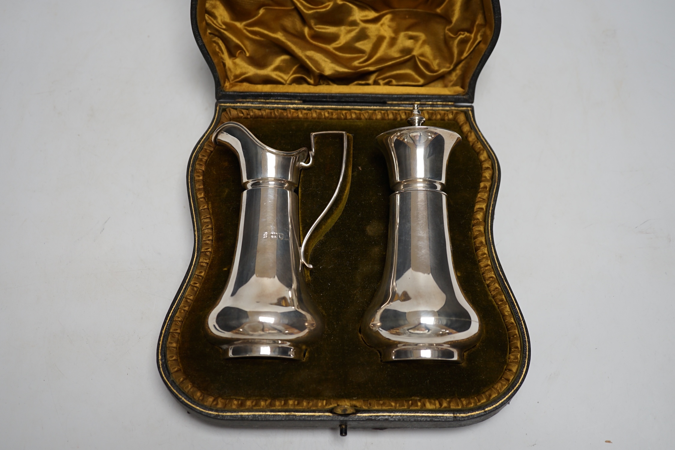An Edwardian cased silver strawberry and cream set, comprising a cream jug and sugar sifter, by Josiah Williams & Co, London, 1906, jug height 13.4cm, 8.5oz.